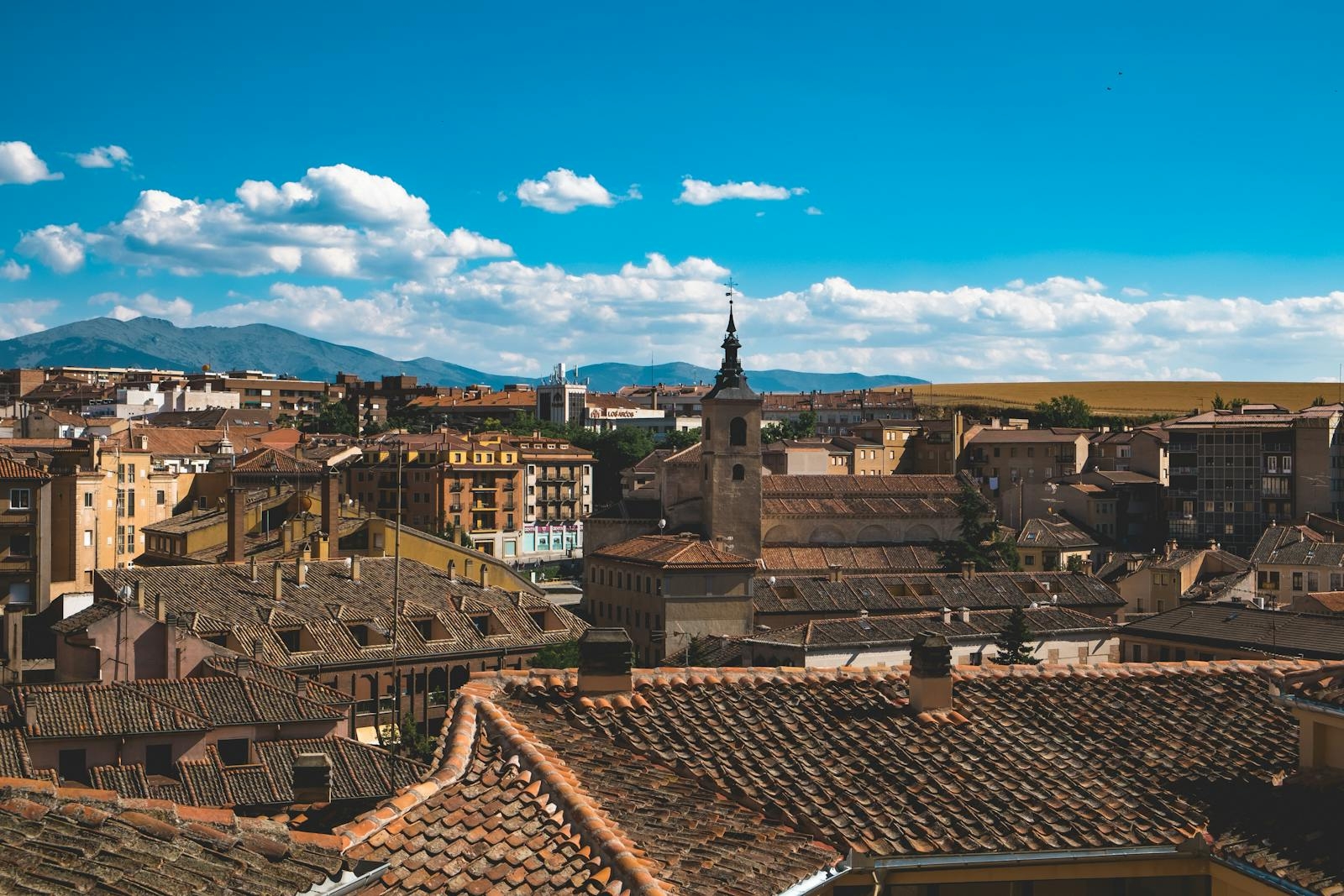 A scenic rooftop view of Segovia, Spain, showcasing historical architecture and vibrant cityscape under a clear blue sky.